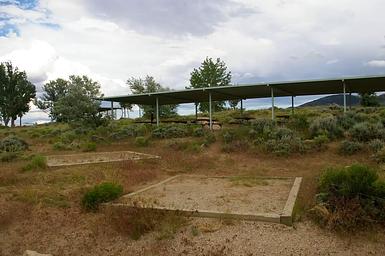 Two tent pads bordered by timbers with a pavillion in the background.