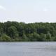 Wide lakeshore view showing the campground’s lake and tree-lined opposite shoreline — good overall scenic photo of on-site Otter Lake (primary hero image from the campground home page).