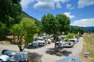 Elevated view of RV sites and internal roadways with trees and mountains in background — clear depiction of RV pitches and site spacing (from the rates/amenities pages).