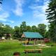 Covered picnic pavilion in a grassy central area with surrounding trees and campground structures visible — good view of a shared amenity from the gallery page.