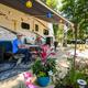 Close view of an RV campsite with awning, patio setup and landscaping — shows typical RV pitch and guest setup on the property (matches homepage/gallery context).