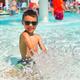 Close-up of a child splashing in a pool — highlights the onsite swimming/water play amenity and family-friendly atmosphere.