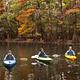 Three children kayak on the water in the autumn