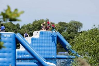 People enjoying an inflatable water obstacle course on a sunny day.