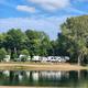 Lakeside RV sites and shoreline reflected in water, clearly showing RV pitches and campsite setting — sourced from the site gallery/background images on the property website.