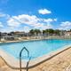 Outdoor swimming pool on-site with fenced deck, lounge chairs and RVs/buildings visible in the background — matches the campground Amenities/gallery page showing the pool.