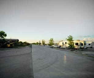 Perspective of park road and several parked RVs on concrete pads, illustrating site layout and roadway — corresponds to the rates/site layout photos on the property site (page: /rates).