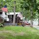 Row of RV sites with decks and American flags along a tree-lined drive — good depiction of site spacing, decks and mature trees on the property (IMG_0660.jpg from the camping page).
