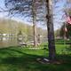Grassy lakeside view with docks, small boats and RVs/campsites along the shore — clear depiction of the campground shoreline and pitches (homepage slider).