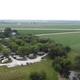 High aerial view showing RV loop, several parked RVs, campground layout, surrounding farmland and a small pond — useful overall overview of the property.