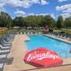 Elevated view of the heated outdoor pool with lounge chairs and part of the campground beyond — shows pool facility and nearby RV/campsite area.