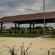 Shows a large covered pavilion, picnic tables and a playground with open grassy RV/campsite area — a clear photo of on-site recreation/facility from the property's homepage background image.