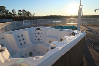 Close-up of a hot tub on the rooftop/deck area with the park and horizon in the background — highlights a notable amenity.