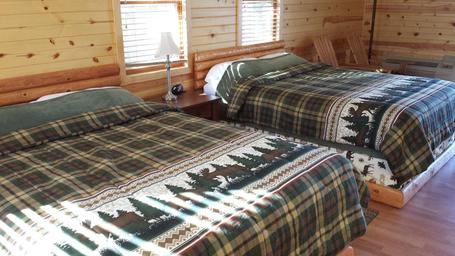 Interior bedroom with two beds in a wood-paneled rental unit — clearly from the Rentals page, shows on-site lodging accommodations.
