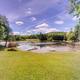 Wide landscape view showing the campground pond, dock and surrounding grassy shore — good aerial/overview image of on‑site water feature and grounds (matches homepage/gallery pond photos).