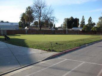 Grassy field area adjacent to paved roadway within the park — a property photo listed on the site's Photos page that helps show on-site open space and layout.