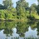River or pond reflection framed by trees—illustrates nearby water scenery and natural setting presented on the park website.