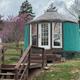 Front view of a yurt with French-door entrance and stairs, set on a grassy knoll — highlights accommodation style and access features.