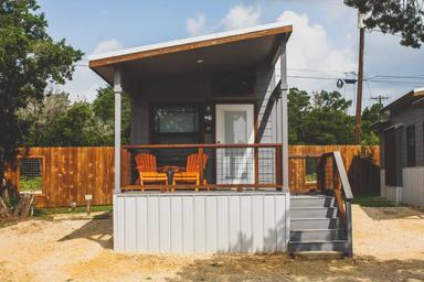 Front view of a single tiny cabin with porch and seating — good close-up of individual cabin type and site finishings; image is on the resort site.