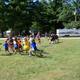 Open grassy recreation area with RVs in the background and campers participating in activities—illustrates campground common space and family-friendly events from the Facilities/The Park page.