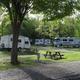 Grassy campsite foreground with picnic table and several parked RVs in the background — another clear view of site spacing and amenities from the Campground Amenities page.