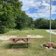 Open grassy recreation area with picnic table, horseshoe/sand pits, flagpole and campground road — useful to show on-site outdoor amenities (from Amenities page).