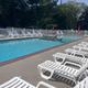 Outdoor swimming pool with white lounge chairs and red umbrellas on a sunny day