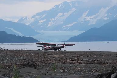 A wheeled airplane parked on the beach after landing near the cabin. A beach plane landing depends on the tide and if there are icebergs on the beach.