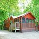 Shows a screened cabin on a gravel site surrounded by trees — clear photo of on‑site cabin accommodation. Appears on the property’s main site gallery (page context: accommodations).