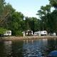 Wide waterfront view showing a row of RVs along the riverbank — large image from the campground ‘Rates & Reservations’ page and clearly depicts on-site RV sites along the Mississippi.