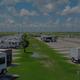 Wide perspective-level photo along the RV rows showing multiple full hookup sites, paved roads and site spacing — useful hero-style image of the campground (source: site hero image).