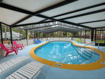 Covered outdoor pool area with loungers and RV visible in background — highlights on-site recreation facility.