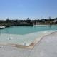 Clear photo of the swimming pool with the RV park visible in the background — highlights on-site recreational amenity. Shown on the property homepage/accommodations content.