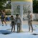 Splash pad / waterpark photo with kids under a mushroom fountain — shows the campground’s pool/water play facility mentioned on the site.