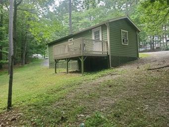 Standalone raised cabin in a wooded setting — good distinct close-up of cabin type and site surroundings, matching cabin images on the campground site.