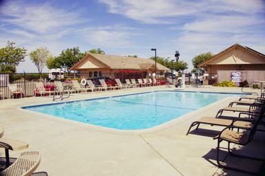 Alternate pool-facing shot with lounge chairs and clubhouse visible — clear depiction of the resort’s swimming amenity and seating areas from the homepage imagery.