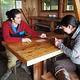 Two people playing cards inside a wood cabin