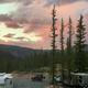 On-site campsite shot at sunset showing RVs, an off-road vehicle and the campground road with surrounding forested mountains — useful for campsite ambience and setting.