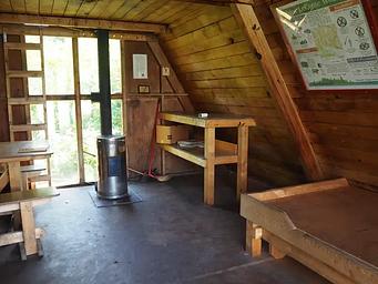 Shakes Slough 2 Cabin interior showing wood bunk, table stove and vertical ladder to loft