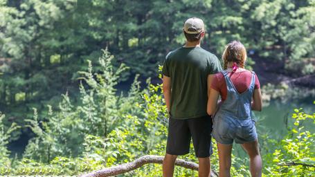 Scenic view of two people overlooking the pond and wooded shoreline — shows the pond scenery and trails/overlook areas on the property.