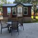Small cabin exterior (deluxe cabin) with patio furniture visible — matches the site’s 'deluxe cabins' / accommodations photos on the campground page.