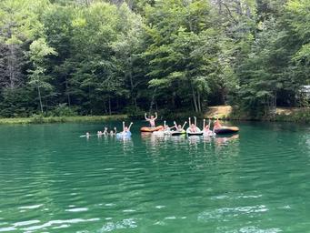 Activity at the pond with swimmers/floaters in the water — demonstrates recreation opportunities available on the property (from home page imagery).