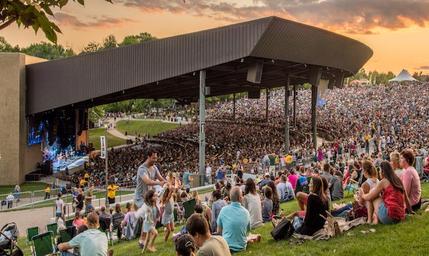 Wide daytime photo of the Bethel Woods pavilion and surrounding lawn seating with crowds — shows the main event venue and adjacent grounds, useful for conveying the site’s facilities (from the site homepage).