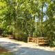 Clear on-property campsite / RV pad view: gravel drive, picnic table, fire ring and utility pedestal visible. Sourced from the campground HOME page as a hero/gallery image showing site amenities.