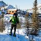 A man snowshoes from a log cabin