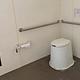 A toilet in the pit toilet building with rolls of toilet paper on the left.