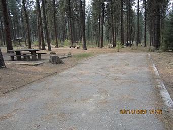 A long paved driveway next to a single campsite.