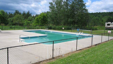 Photograph of the on-site swimming pool, fenced and with surrounding grounds — documents recreational facility (homepage image).