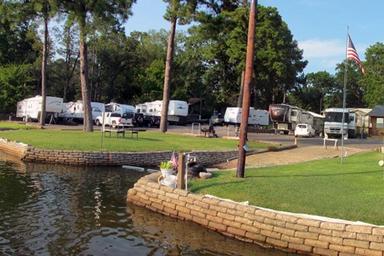 View of the RV pitches along the water with site landscaping and seawall — good depiction of the park’s RV area and shoreline (from the site’s gallery).