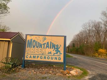 Entrance sign reading 'Mountain Creek Campground' beside the road with campground context and landscape — useful identifying shot for the property (gallery image).